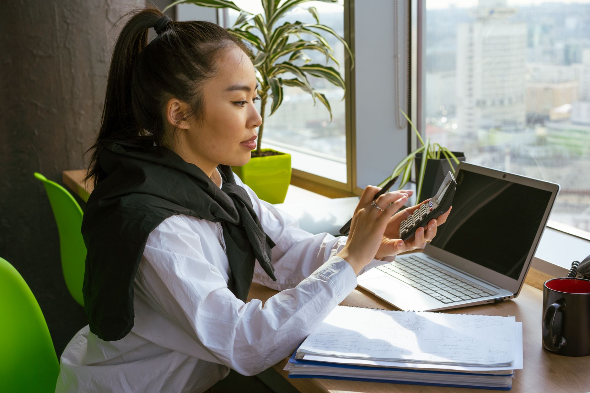 a cost accountant reviewing figures at a laptop in a bright office